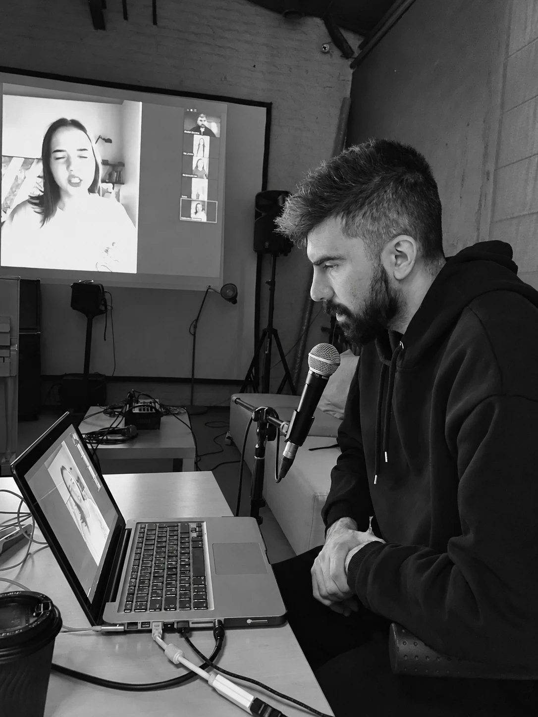 Mikhail Kasymov teaching an online vocal lesson: a student sings on screen while he listens at the microphone